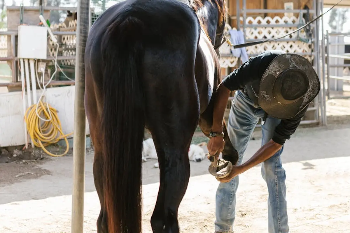 Smiling woman with a towel wrapped around her head, applying foamy face wash in a bathroom.