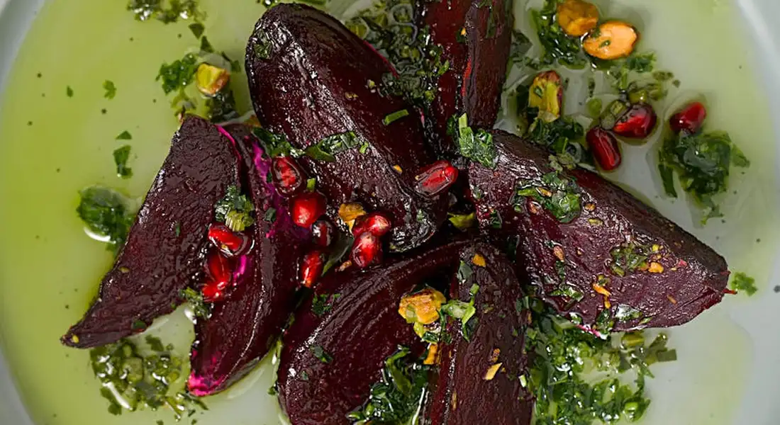 Beetroot slices with herbs and seeds on a green plate