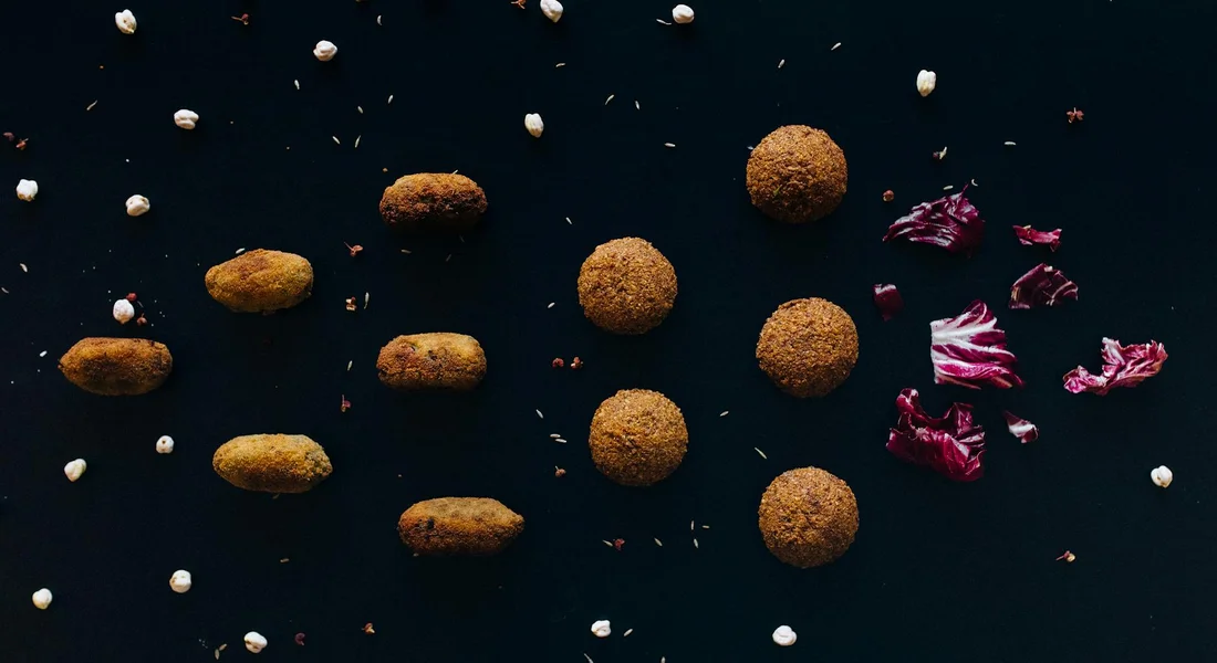Scattered horse feed pellets with pieces of purple cabbage on a dark surface