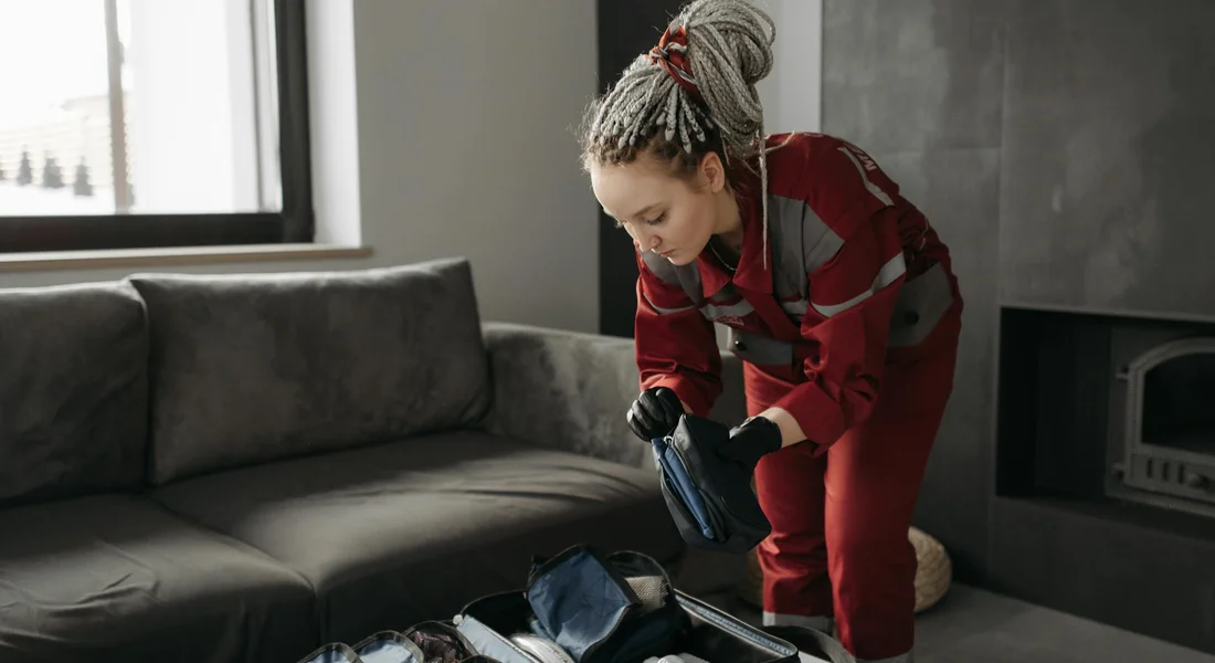 Person organizing a first aid kit indoors, checking supplies for maintenance.