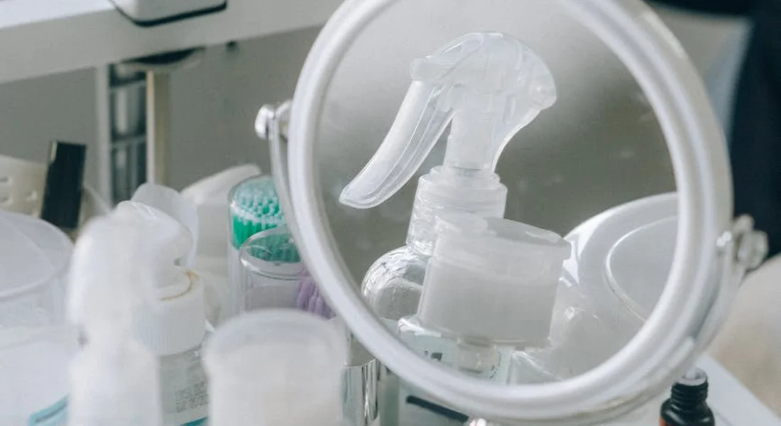 Close-up of disinfectant spray bottles and grooming tools on a grooming station with a circular mirror reflecting the equipment