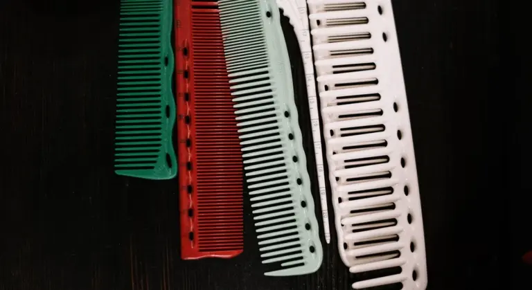 Colorful plastic combs arranged in a row on a dark wooden surface.