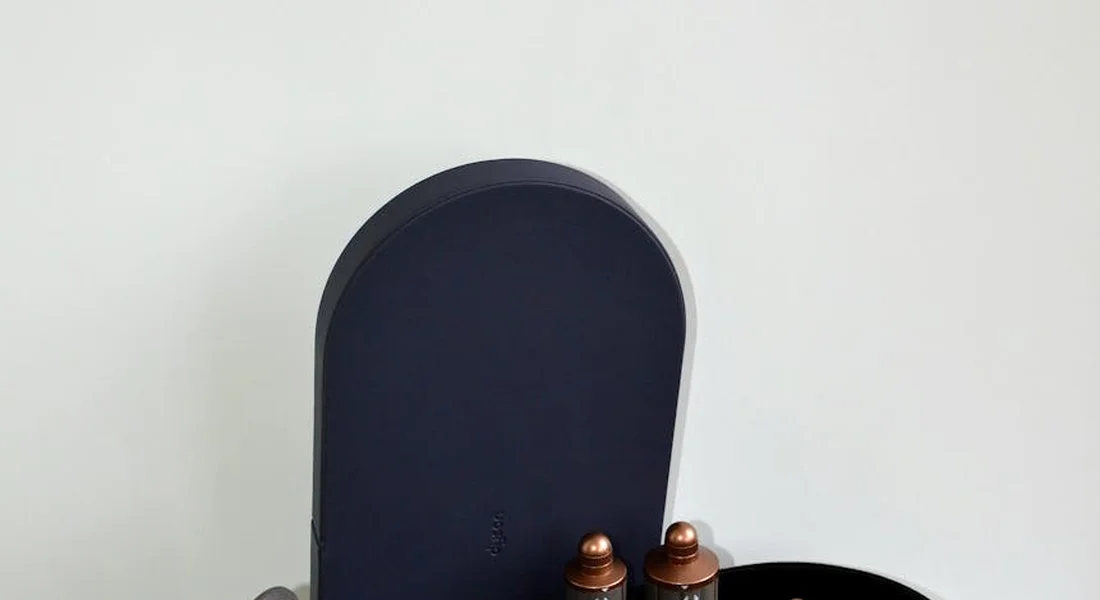 Grooming kit with a dark blue curved case and two small brown bottles on a light surface