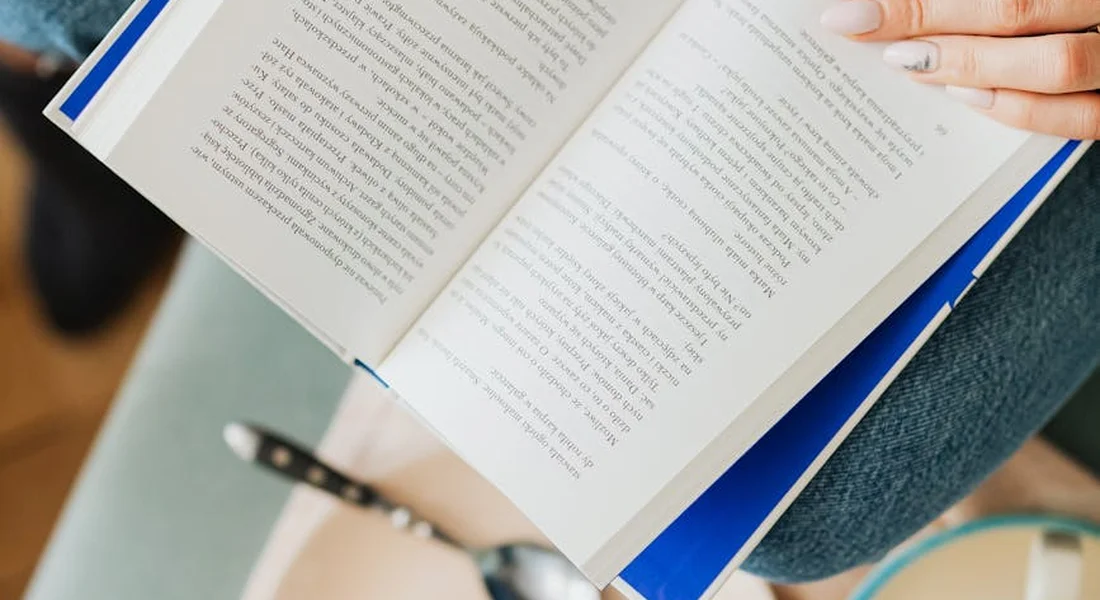 Person reading an open book, illustrating research and evaluation of horse feeding options