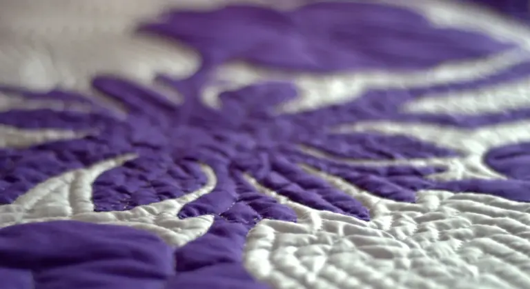 Close-up of a purple quilted blanket with white stitching, similar to a horse blanket
