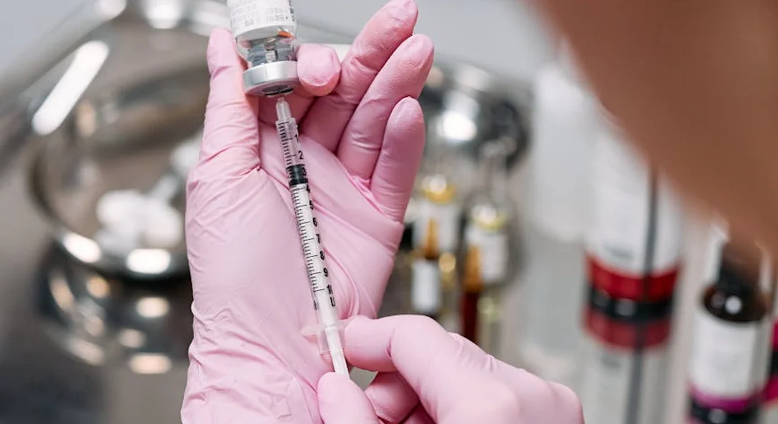 Close-up of gloved hands preparing a syringe with medication, ready for an injection