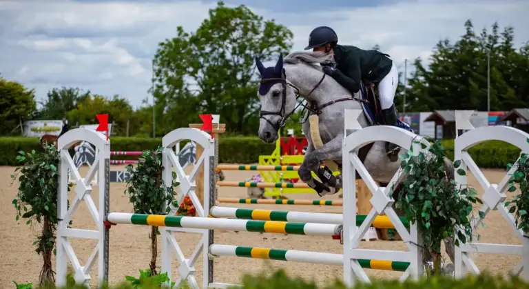 Horse and rider jumping over a colorful training jump in an outdoor arena