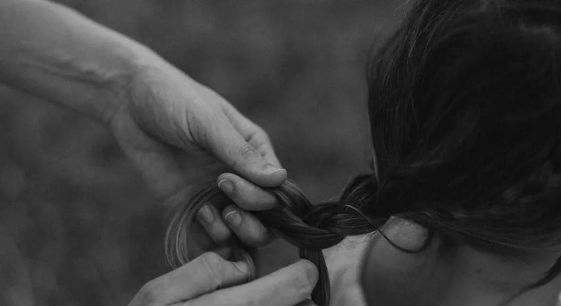 Close-up of hands braiding a horse's mane, showing a common braiding technique.