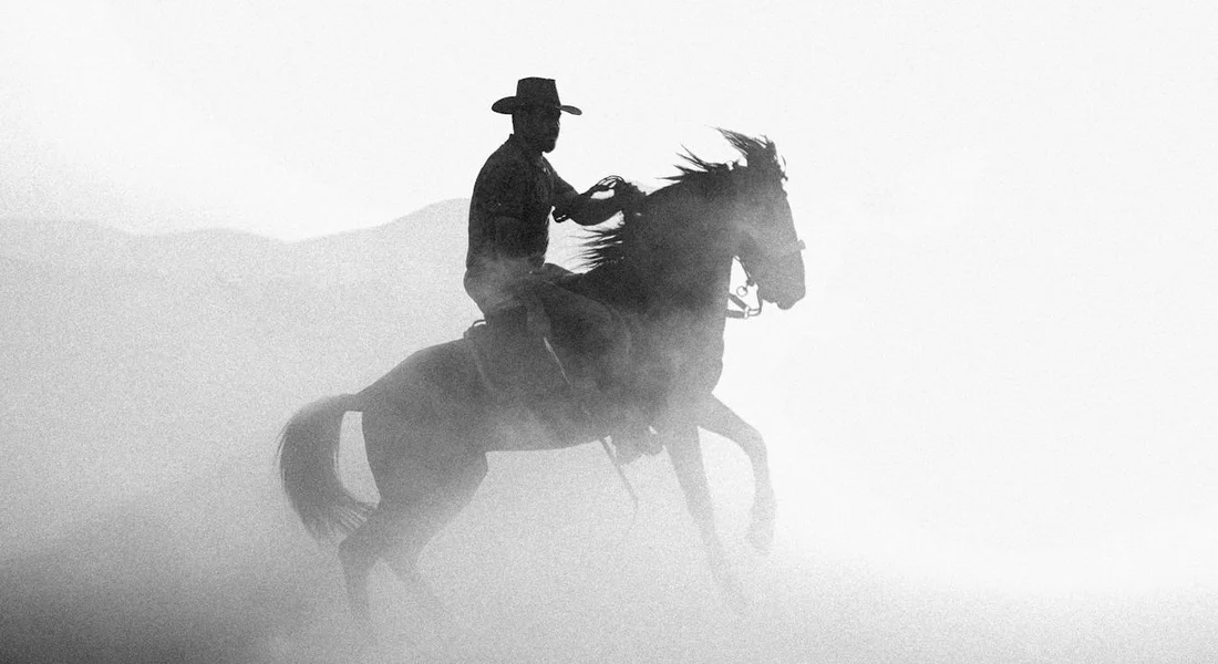 Silhouette of a rider on a powerful horse galloping through dust