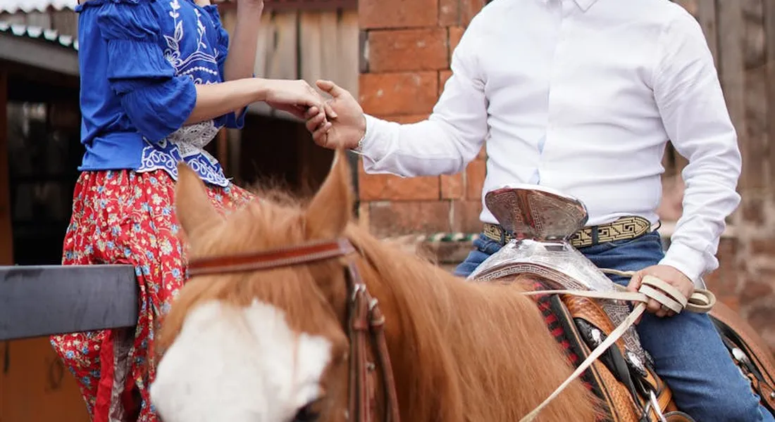 Two helpers assist a rider mounting a brown horse, illustrating safe mounting for beginners.