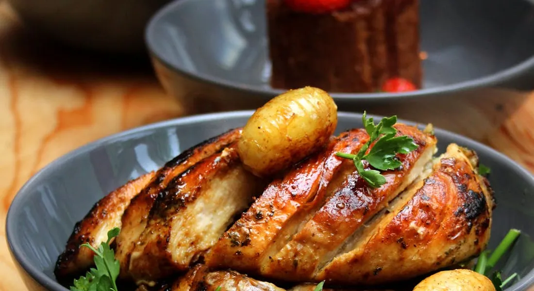 Plate of roasted chicken with roasted potatoes garnished with parsley on a wooden table