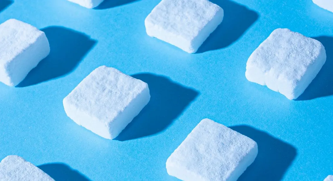 White sugar cubes scattered on a bright blue surface
