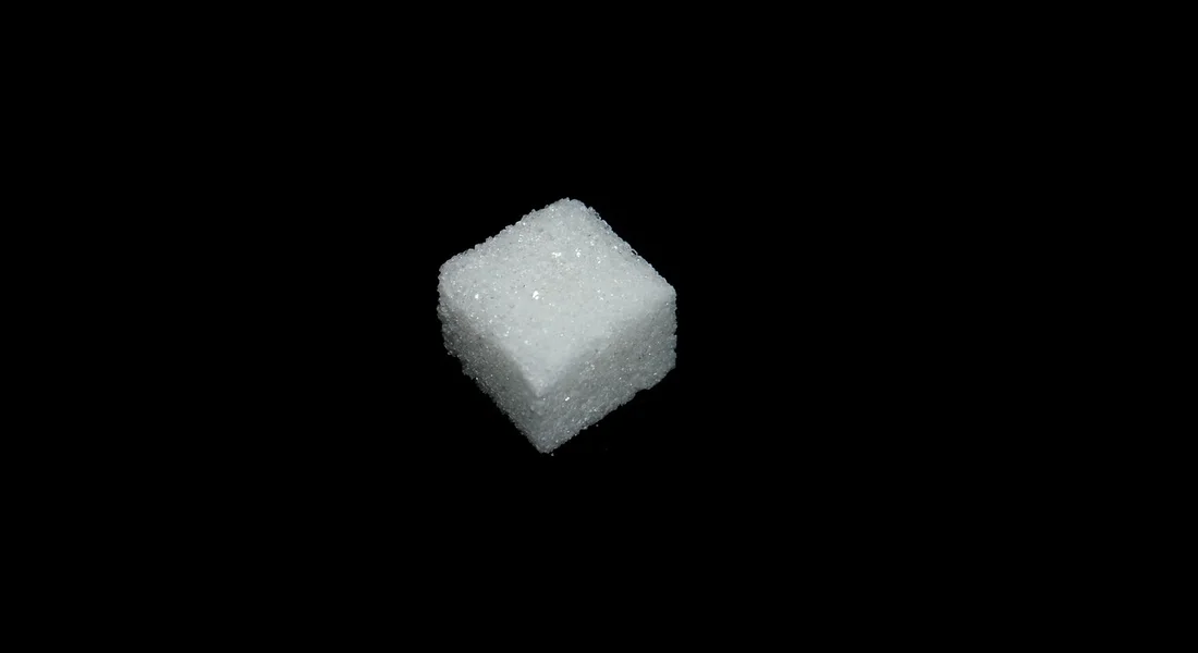 Close-up of a single white sugar cube on a black background